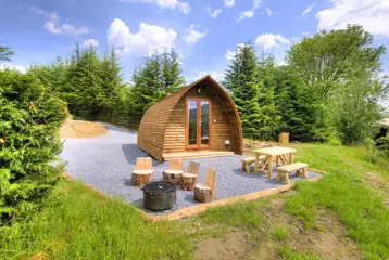 Premium ensuite glamping pods with picnic bench and wood carved stools Premium ensuite glamping pods with picnic bench and wood carved stools
