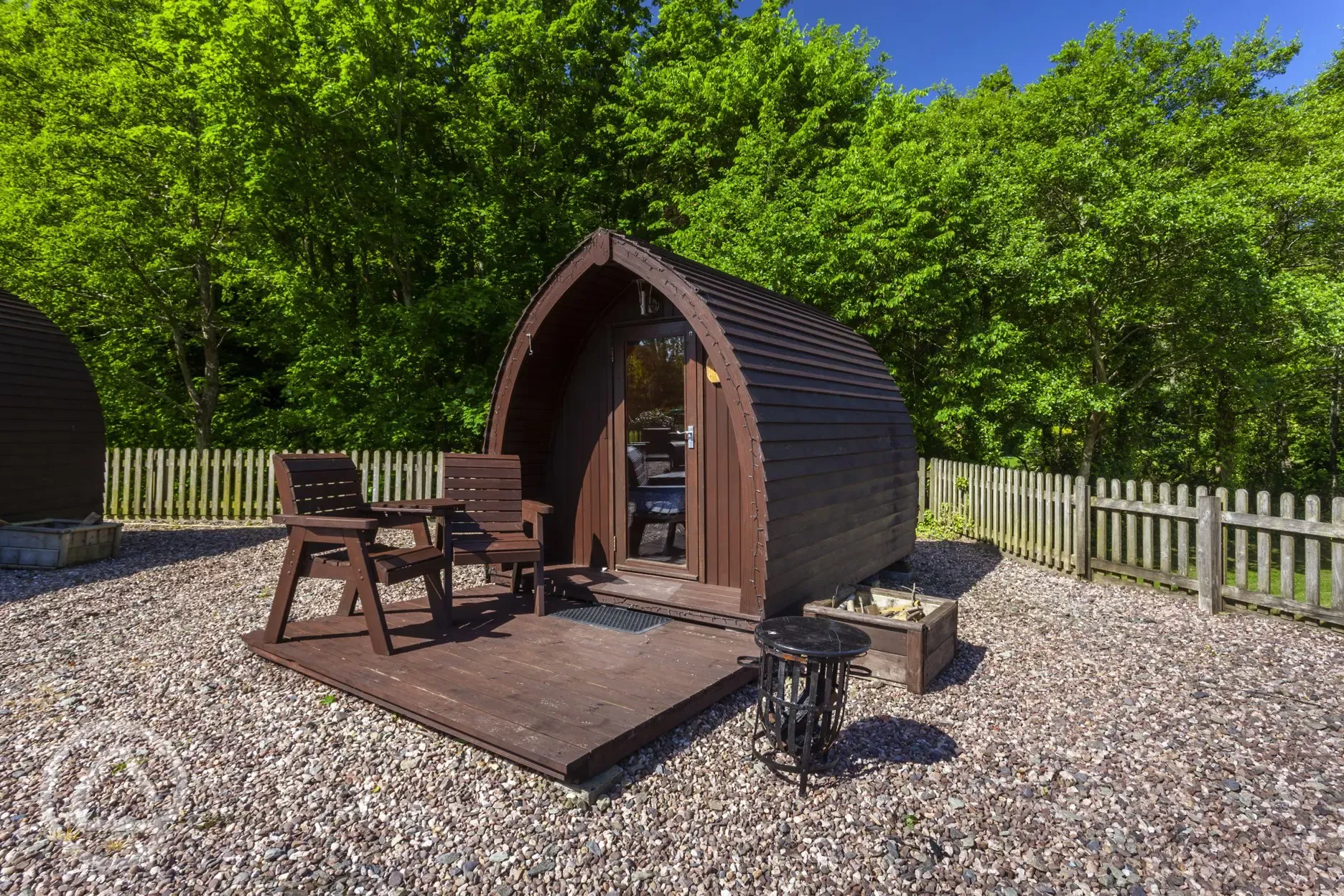 Camping pod with decking, chairs, and a fire pit