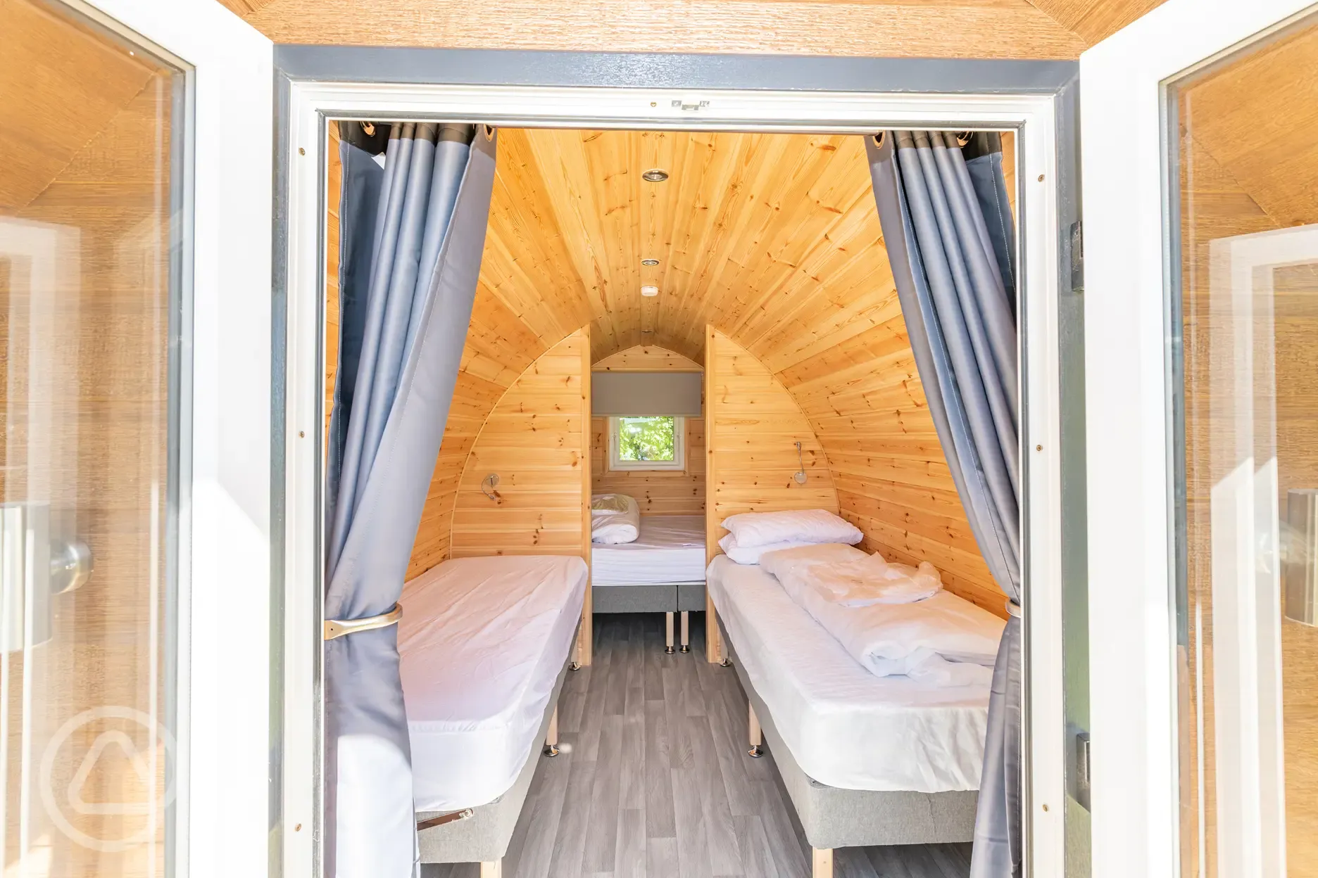 Bronze camping pod interior with double bed and two single kids camp beds