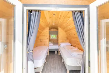Bronze camping pod interior with double bed and two single kids camp beds Bronze camping pod interior with double bed and two single kids camp beds