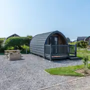 Bronze camping pod exterior with outdoor seating area, and sleeping up to four 