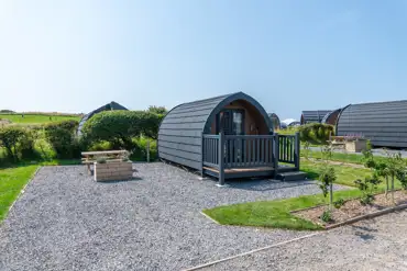 Bronze camping pod exterior with outdoor seating area, and sleeping up to four 