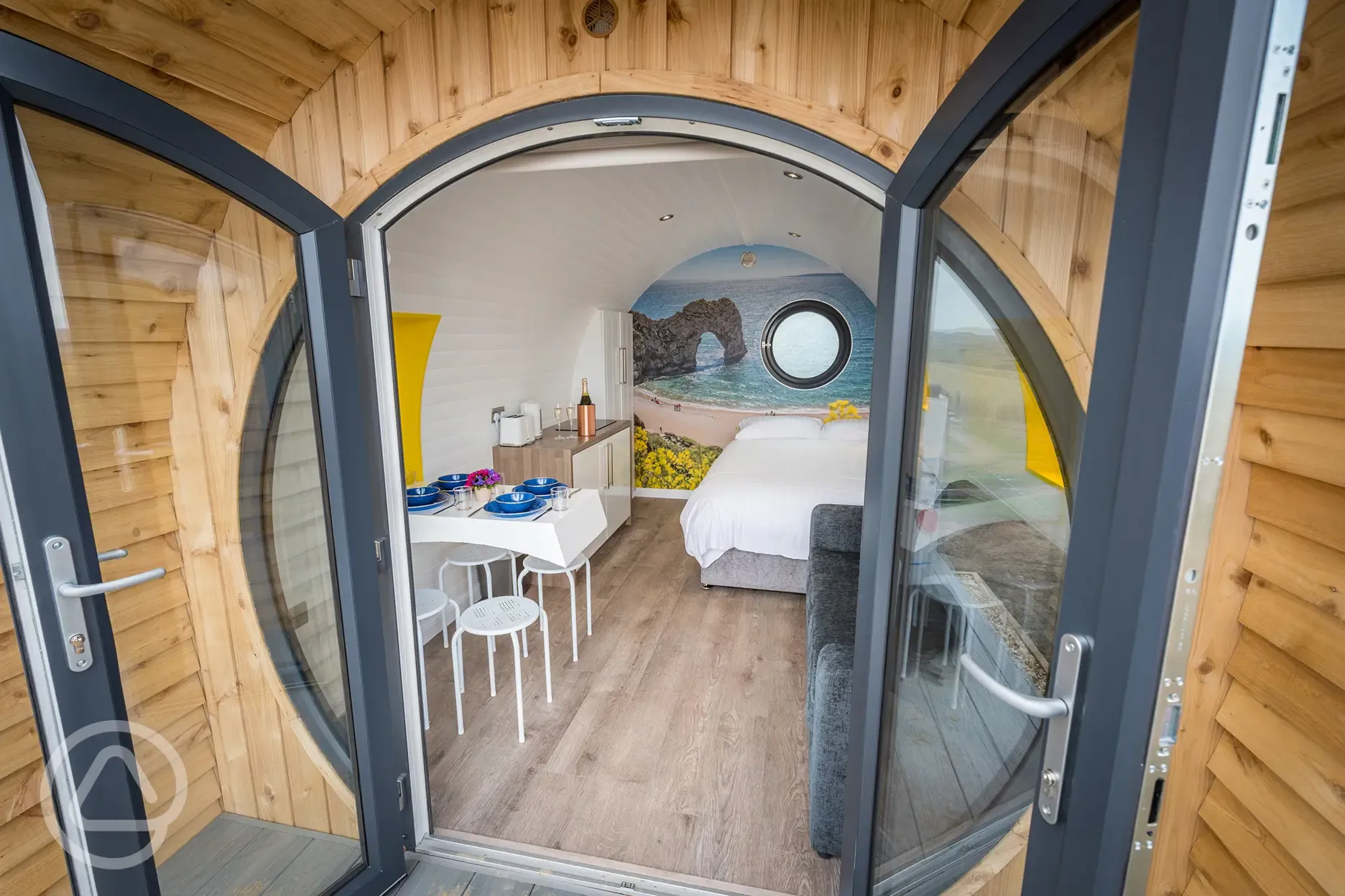 Silver glamping pod interior with double bed, sofa bed, kitchenette and seating