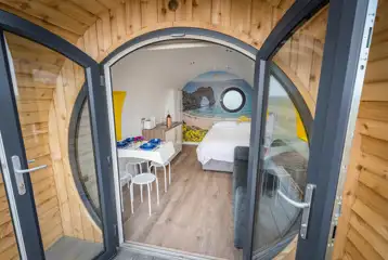 Silver glamping pod interior with double bed, sofa bed, kitchenette and seating Silver glamping pod interior with double bed, sofa bed, kitchenette and seating