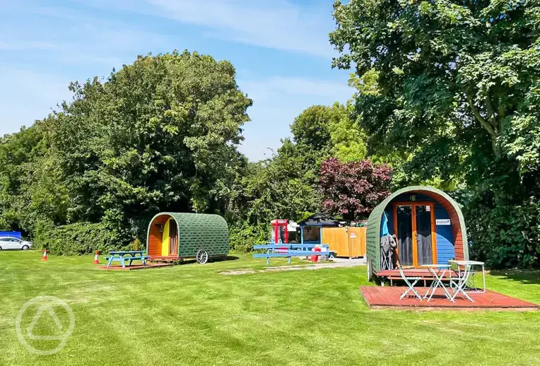 Wooden painted camping pods with deck areas and outdoor furniture