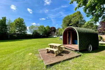 Wooden painted camping pods with deck areas and picnic benches