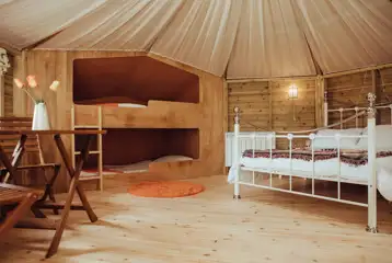 Glamping cabin interior with a double bed and two single bunk beds Glamping cabin interior with a double bed and two single bunk beds