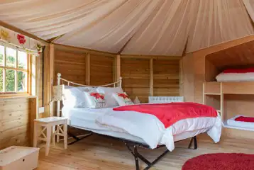 Glamping cabin interior with a double bed and two single bunk beds Glamping cabin interior with a double bed and two single bunk beds