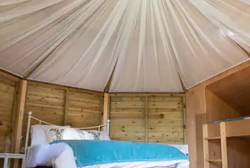 Glamping cabin interior with a double bed and two single bunk beds Glamping cabin interior with a double bed and two single bunk beds