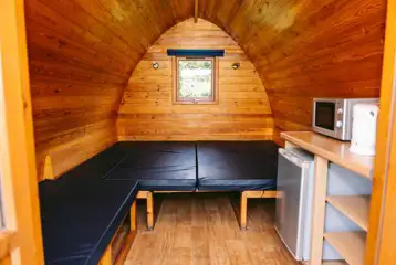 Camping pod interior with microwave, kettle and fridge