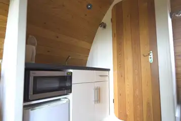 Mega glamping pod kitchen with a fridge, a microwave and kettle 