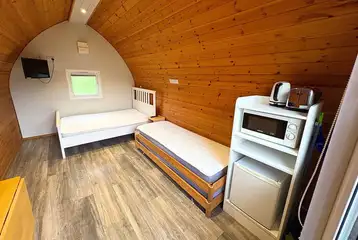Four person camping pod interior with double bed, two singles and kitchenette