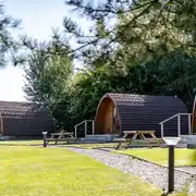 Glamping pods with outdoor deck areas and picnic benches