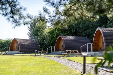 Glamping pods with outdoor deck areas and picnic benches