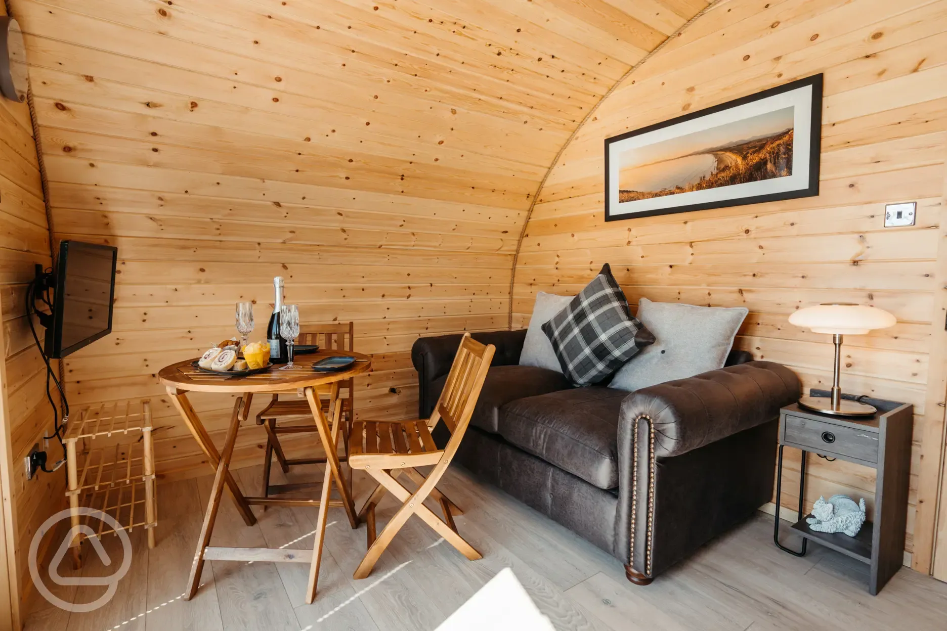 Luxury ensuite glamping pod living area with sofa, dining table and TV
