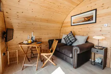 Luxury ensuite glamping pod living area with sofa, dining table and TV Luxury ensuite glamping pod living area with sofa, dining table and TV