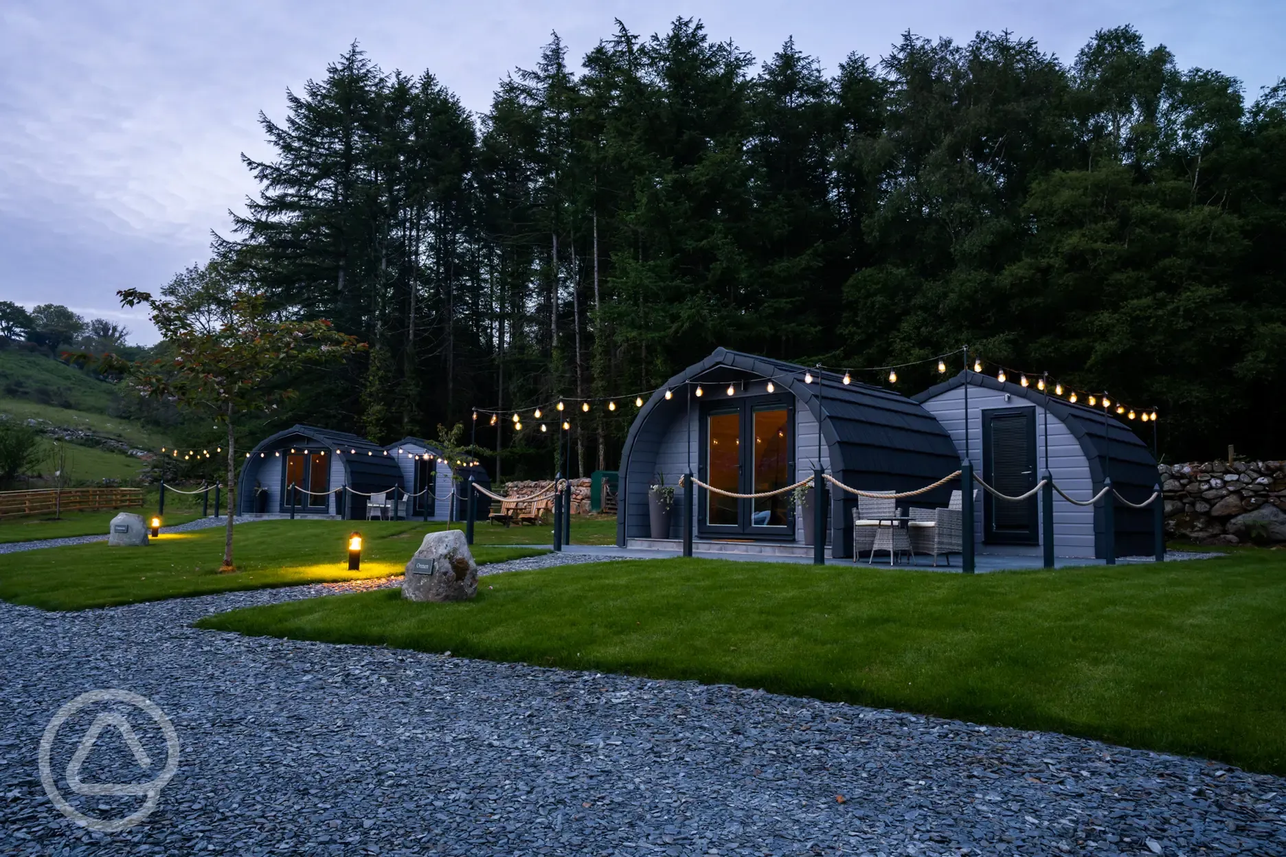 Luxury ensuite glamping pods at night with outdoor festoon lighting