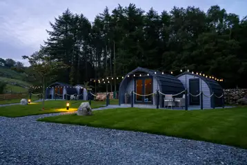Luxury ensuite glamping pods at night with outdoor festoon lighting Luxury ensuite glamping pods at night with outdoor festoon lighting