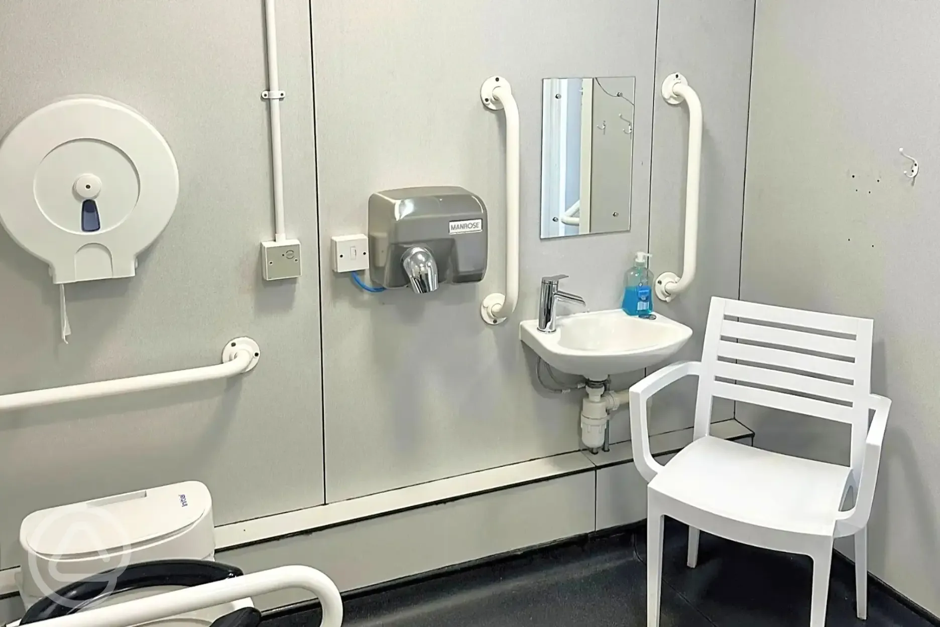 Accessible bathroom with grab rails and a chair
