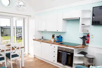 Deluxe beach hut kitchen with a microwave, hob, fridge, kettle and toaster
