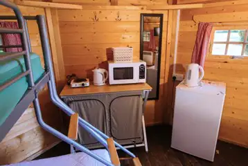 Camping cabin kitchen with fridge, kettle, microwave and coffee table