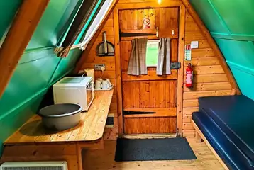 Camping pod interior with four sleeping platforms and a mini kitchen area