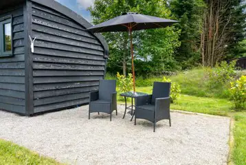 Meadow View glamping cabin outdoor seating area and parasol umbrella