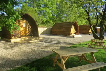 Camping pods with surrounding trees and picnic benches Camping pods with surrounding trees and picnic benches
