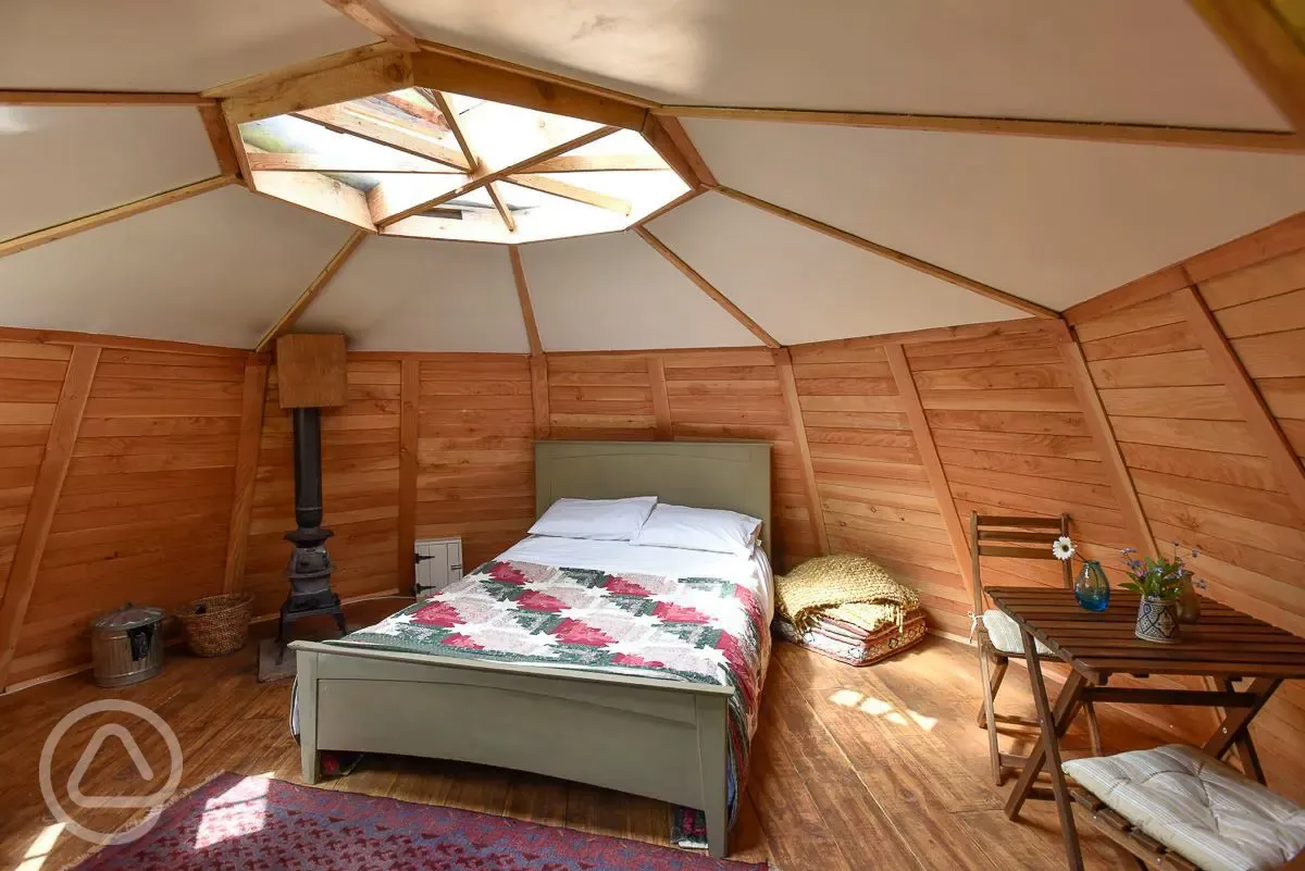 Wooden cabin interior with a double bed and log burner