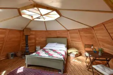 Wooden cabin interior with a double bed and log burner