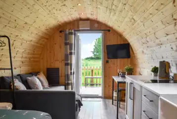 Glamping pod interior with a sofa bed, TV and small table and chairs Glamping pod interior with a sofa bed, TV and small table and chairs