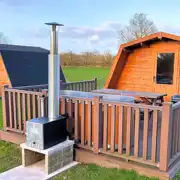 Standard glamping pods with hot tubs with decking area, seating and BBQ outside Standard glamping pods with hot tubs with decking area, seating and BBQ outside
