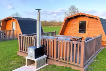Standard glamping pods with hot tubs with decking area, seating and BBQ outside Standard glamping pods with hot tubs with decking area, seating and BBQ outside