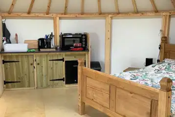 Roundhouse interior with a double bed and kitchenette