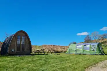 Camping pod and grass pitches with outdoor seating