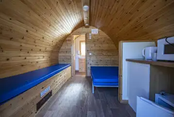 Small ensuite hiker pod interior with double bed, bench and kitchen area Small ensuite hiker pod interior with double bed, bench and kitchen area