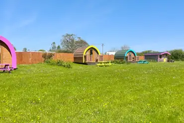 Camping pods with colourful picnic benches
