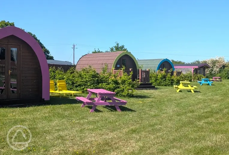 Camping pods with colourful picnic benches