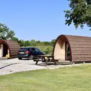 Camping pod exterior with space for a car and outdoor seating