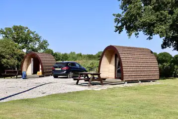 Camping pod exterior with space for a car and outdoor seating