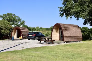 Camping pod exterior with space for a car and outdoor seating
