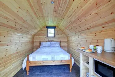 Log pod interior with double bed and bedding provided