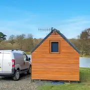 Log pod exterior overlooking the lake with a double bed inside