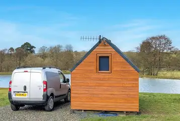 Log pod exterior overlooking the lake with a double bed inside Log pod exterior overlooking the lake with a double bed inside