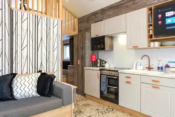 Ensuite glamping cabin interior with a sofa bed, kitchen and mezzanine level