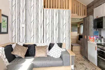 Ensuite glamping cabin interior with a sofa bed, kitchen and mezzanine level