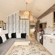 Ensuite glamping cabin interior with a sofa bed, kitchen and mezzanine level