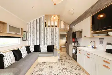 Ensuite glamping cabin interior with a sofa bed, kitchen and mezzanine level
