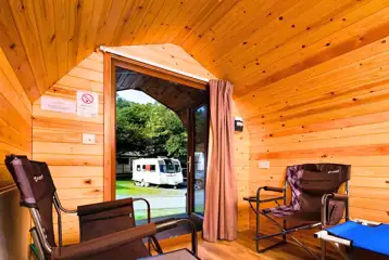 Camping pod interior with two single camp beds, camp chairs and electric sockets