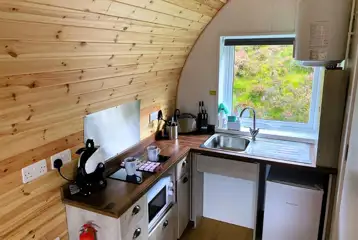 Accessible glamping pod kitchen area with a microwave, fridge, kettle, toaster